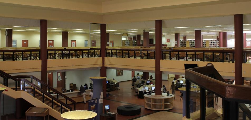 Interior of the University of Venda library showing two floors with pillars, staircase, bookshelves and students using computers