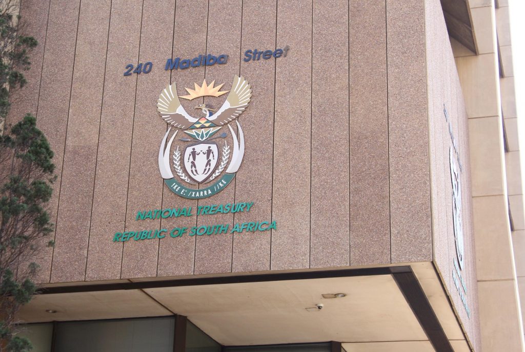 Exterior signage of the National Treasury building at 240 Madiba Street, Pretoria, showing the South African Coat of Arms with the motto !ke e: /xarra //ke, and green text reading NATIONAL TREASURY REPUBLIC OF SOUTH AFRICA on a brown tiled wall.